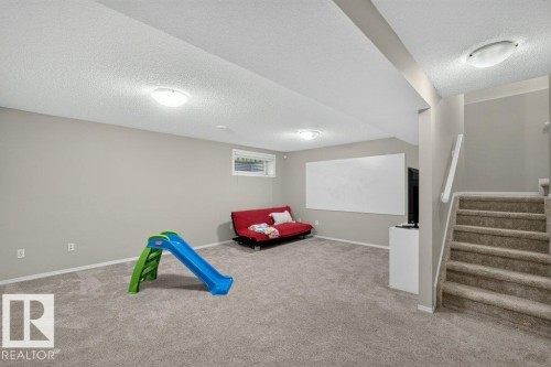 Carpeted flooring, neutral wall paint, overhead lighting, window, and staircase with carpeted steps - #41 287 Macewan Rd Sw, Edmonton, AB 