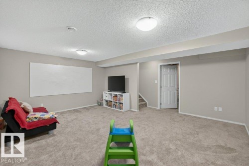 Carpeted recreation room featuring neutral wall tones, recessed lighting, and a paneled door - #41 287 Macewan Rd Sw, Edmonton, AB 