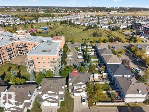 Aerial perspective showcasing a residential neighborhood with green spaces, adjacent multi-story buildings, and varied property types - #41 287 Macewan Rd Sw, Edmonton, AB 