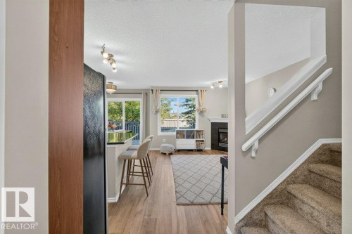 Wood-finish flooring, built-in fireplace, sliding glass door, kitchen island with counter seating, and track lighting - #41 287 Macewan Rd Sw, Edmonton, AB 