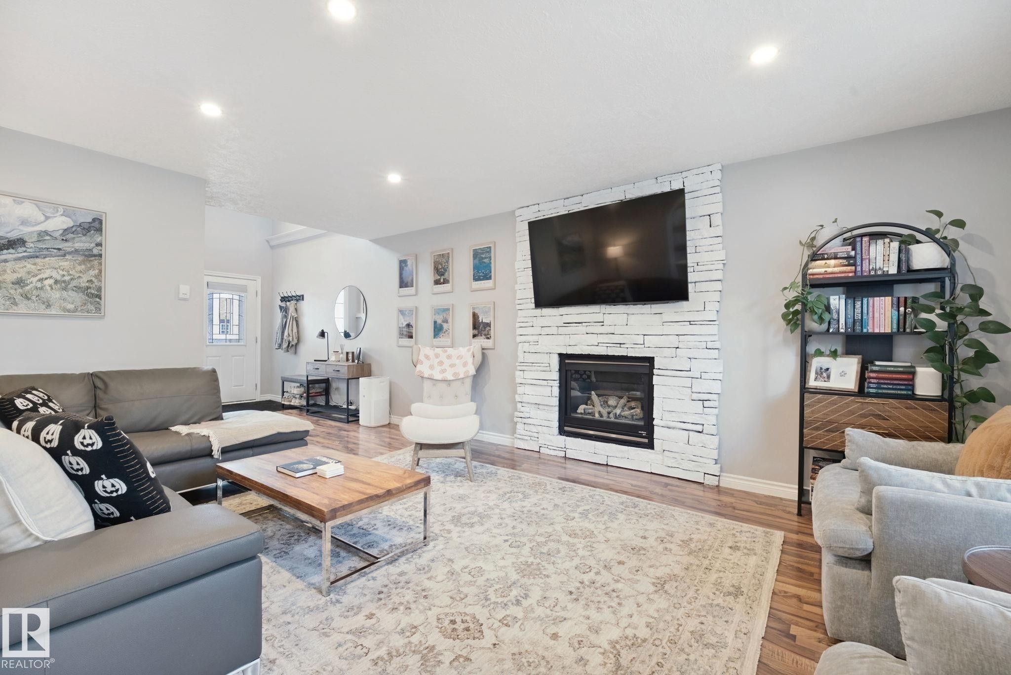 Living area with wood-finish flooring, recessed lighting, and a white stacked stone fireplace - 324 Ascott Crescent, Sherwood Park, AB