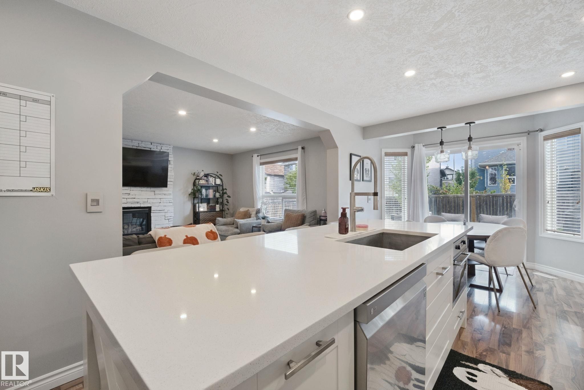 Kitchen island with a built-in stainless steel sink, integrated dishwasher, and white countertop - 324 Ascott Crescent, Sherwood Park, AB