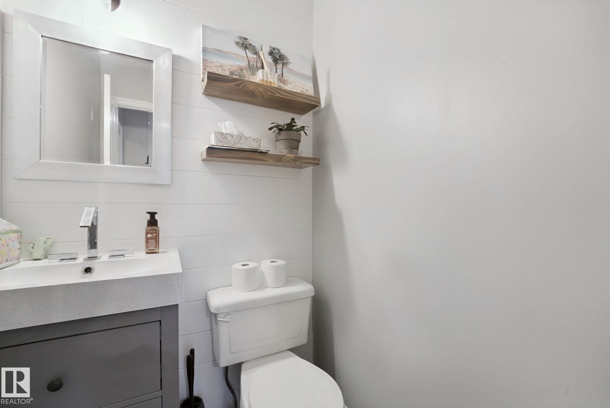 White shiplap accent wall with two wood-finish floating shelves - 324 Ascott Crescent, Sherwood Park, AB