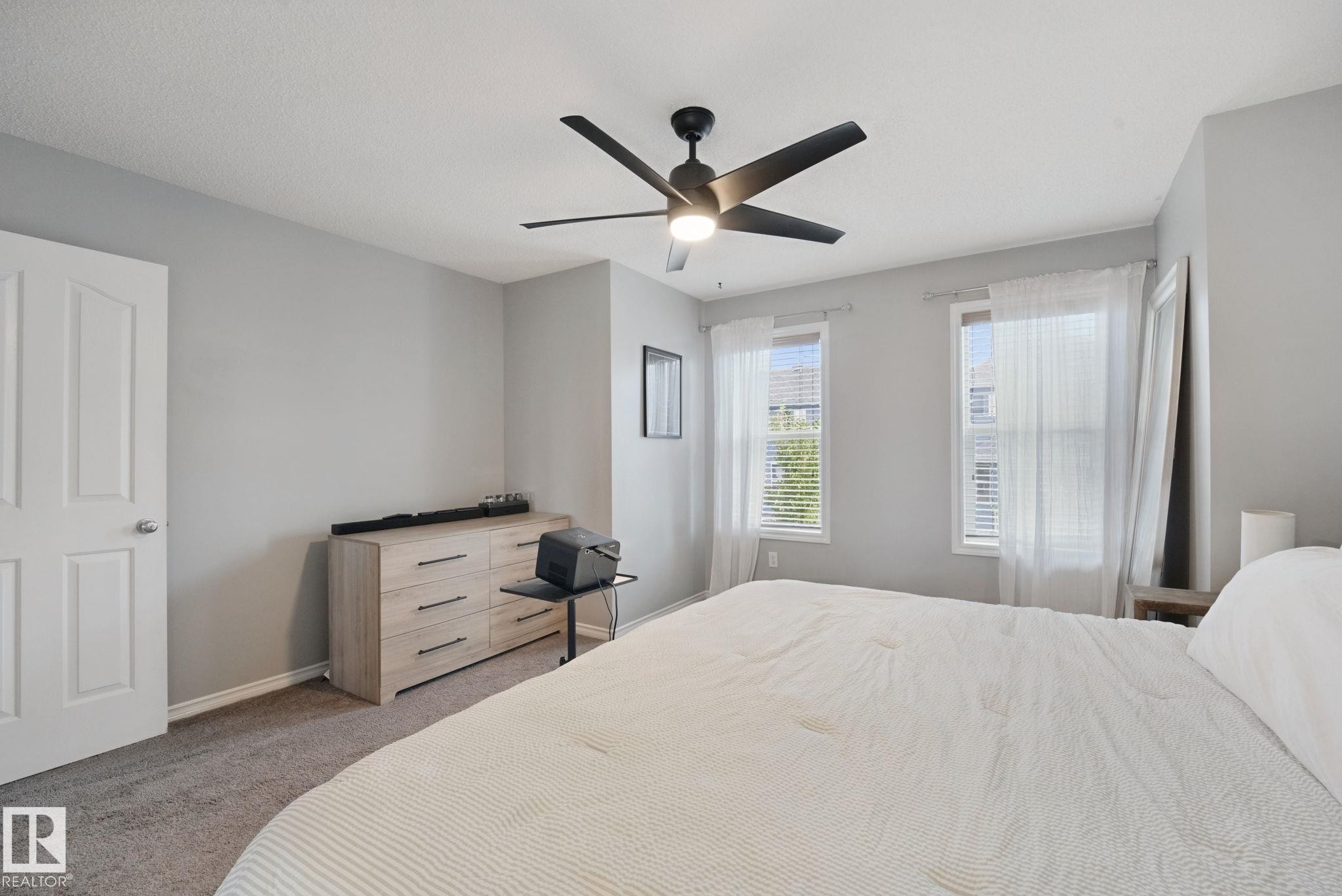 Carpeted bedroom featuring two windows with blinds, a ceiling fan with light, and a solid white door - 324 Ascott Crescent, Sherwood Park, AB