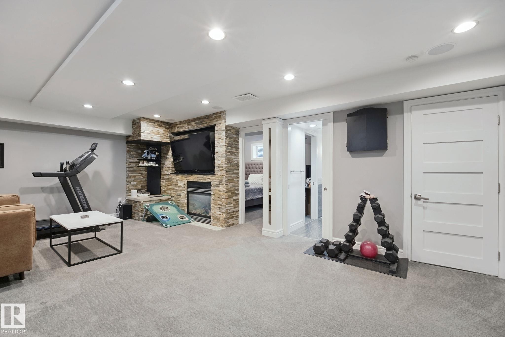 Recessed lighting, stone-clad fireplace, built-in shelving, white paneled doors, and light gray carpet - 324 Ascott Crescent, Sherwood Park, AB