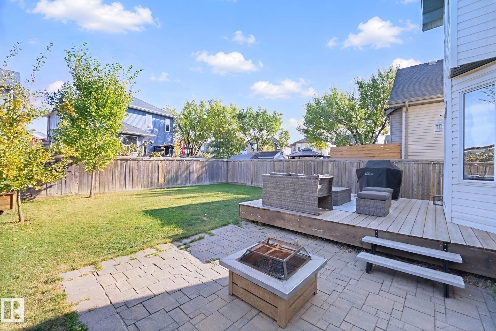 Expansive backyard featuring a lush lawn, paver patio, and a wood deck with steps - 324 Ascott Crescent, Sherwood Park, AB