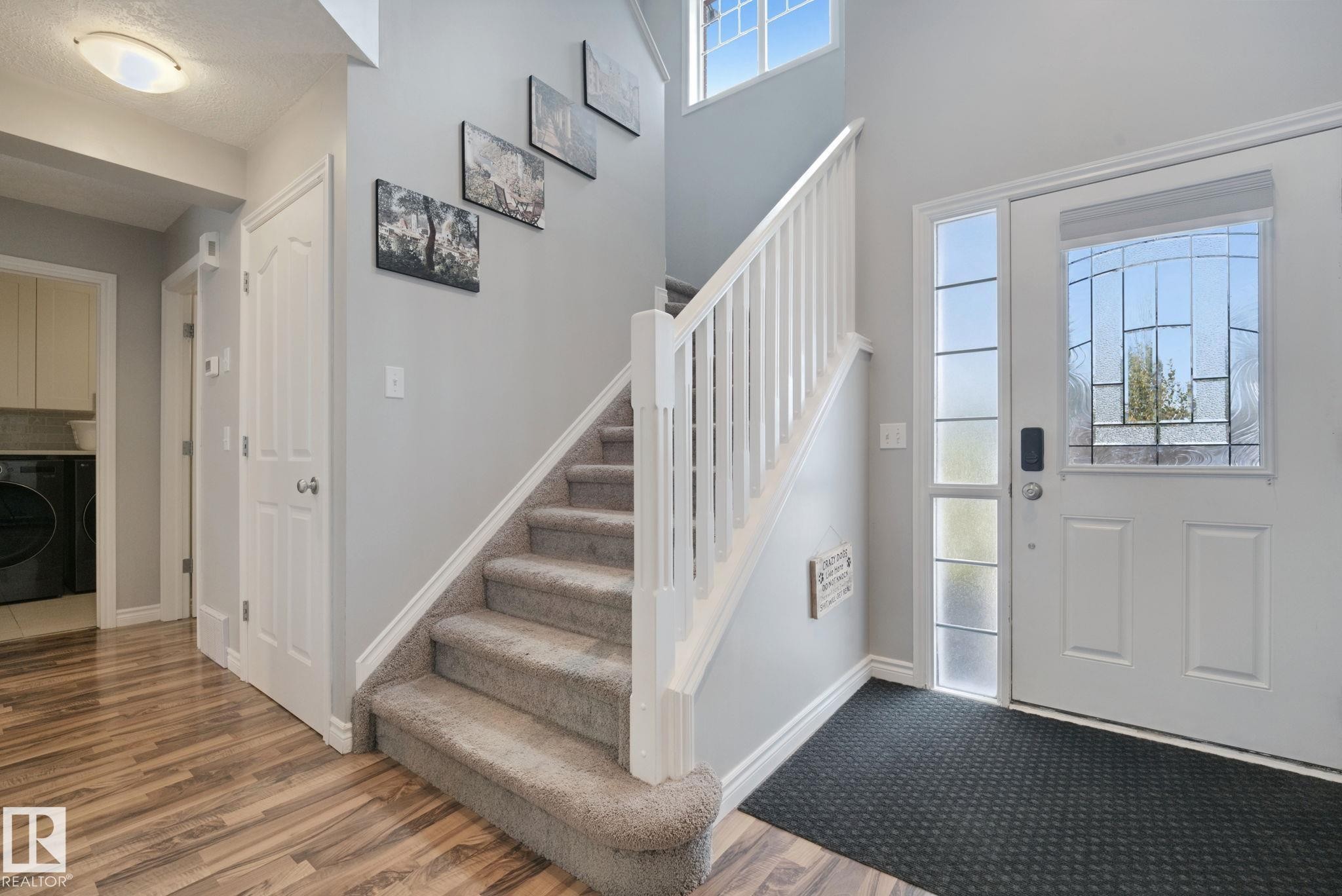 Entryway featuring a white paneled door with decorative glass, a sidelight, and wood-finish flooring - 324 Ascott Crescent, Sherwood Park, AB