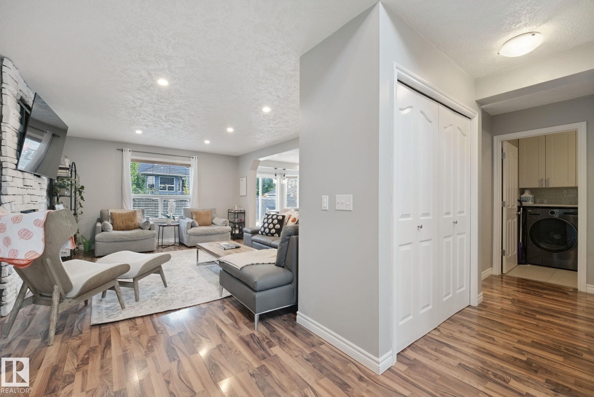 Wood-finish flooring throughout, recessed lighting, and a white painted brick fireplace surround - 324 Ascott Crescent, Sherwood Park, AB