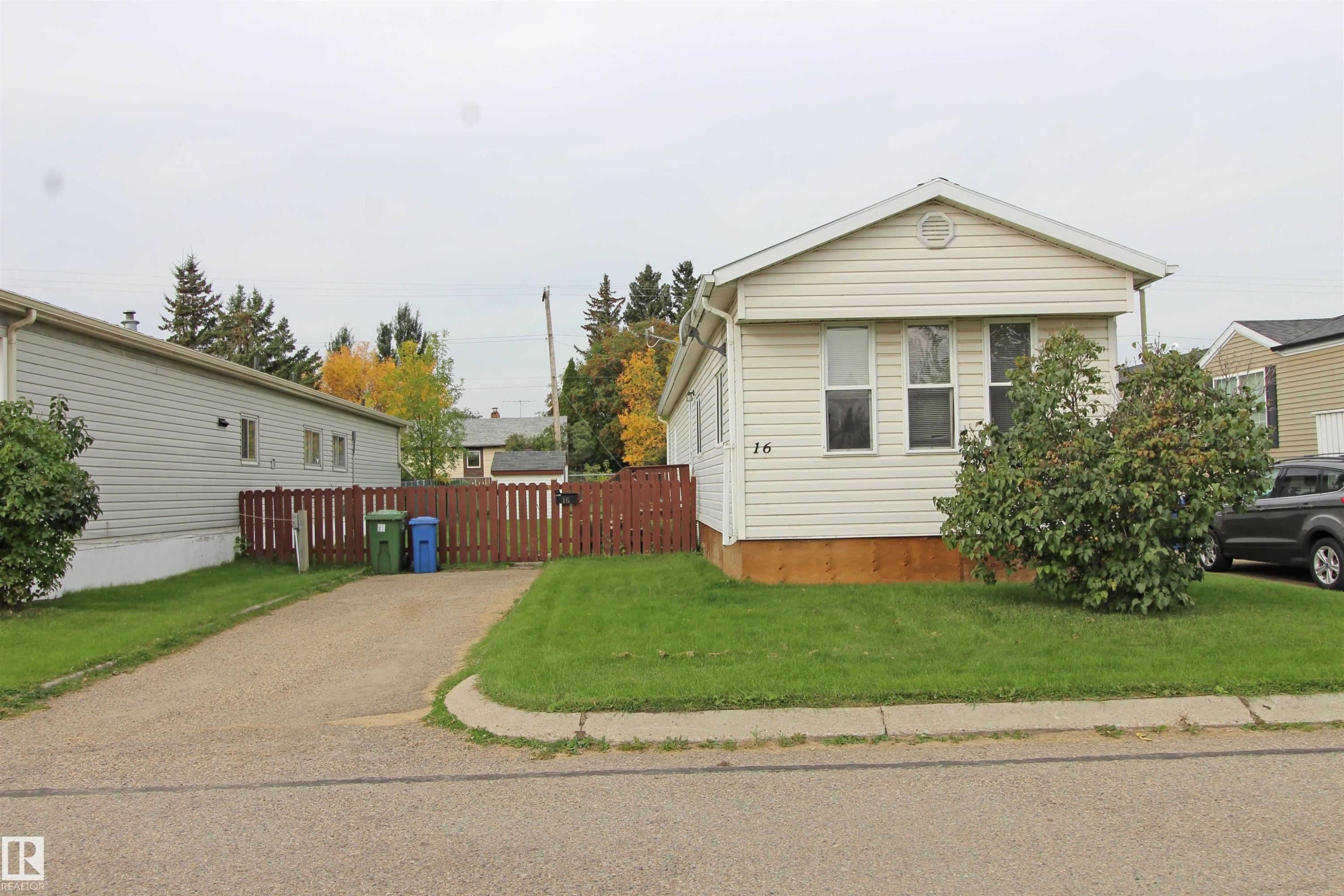 Single-story residence featuring light-colored siding, a pitched roofline, and a manicured front lawn - #16 4202 45 St, Wetaskiwin, AB