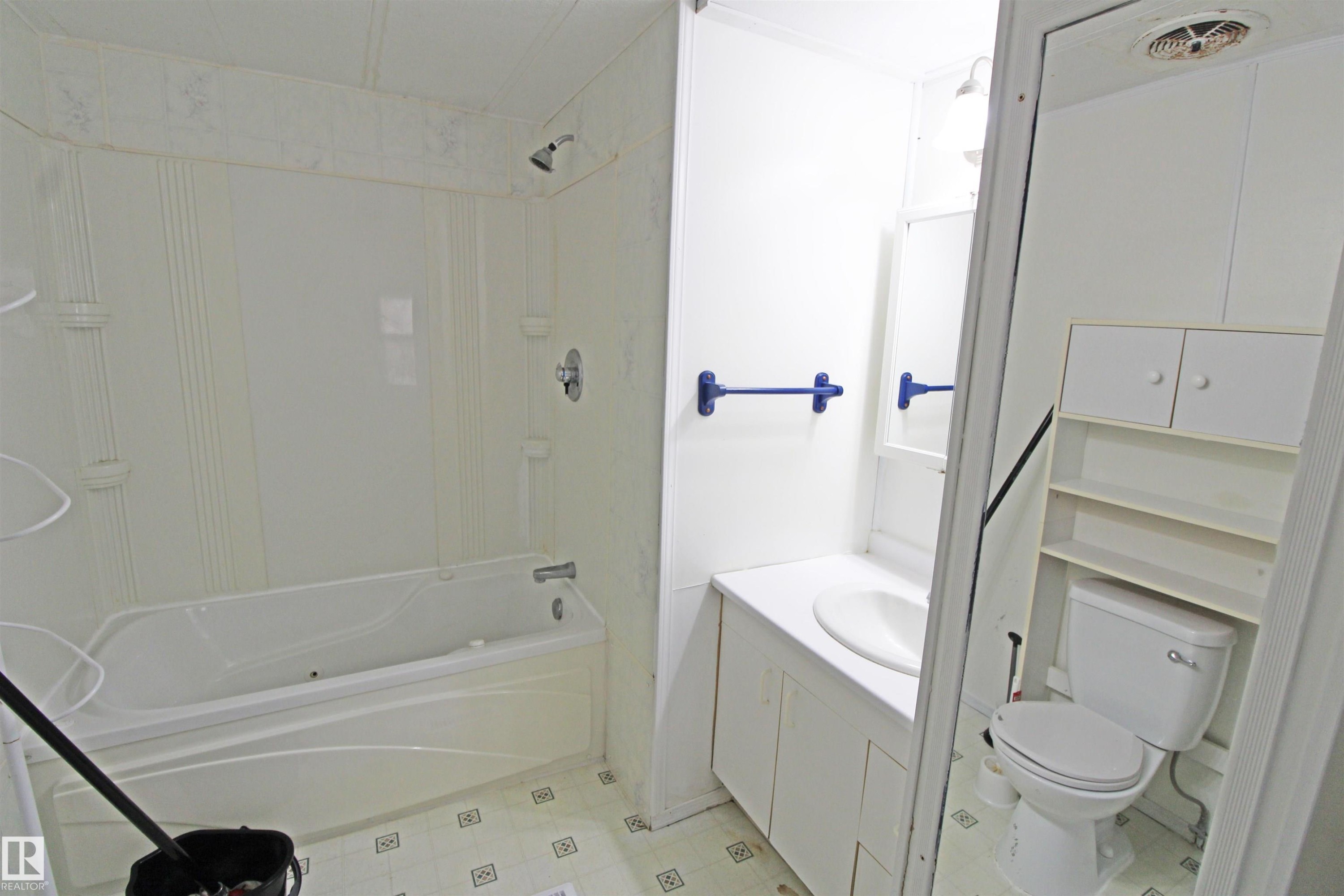 Bathroom featuring a white bathtub with shower, white vanity with integrated sink, white toilet, and built-in white storage shelving - #16 4202 45 St, Wetaskiwin, AB