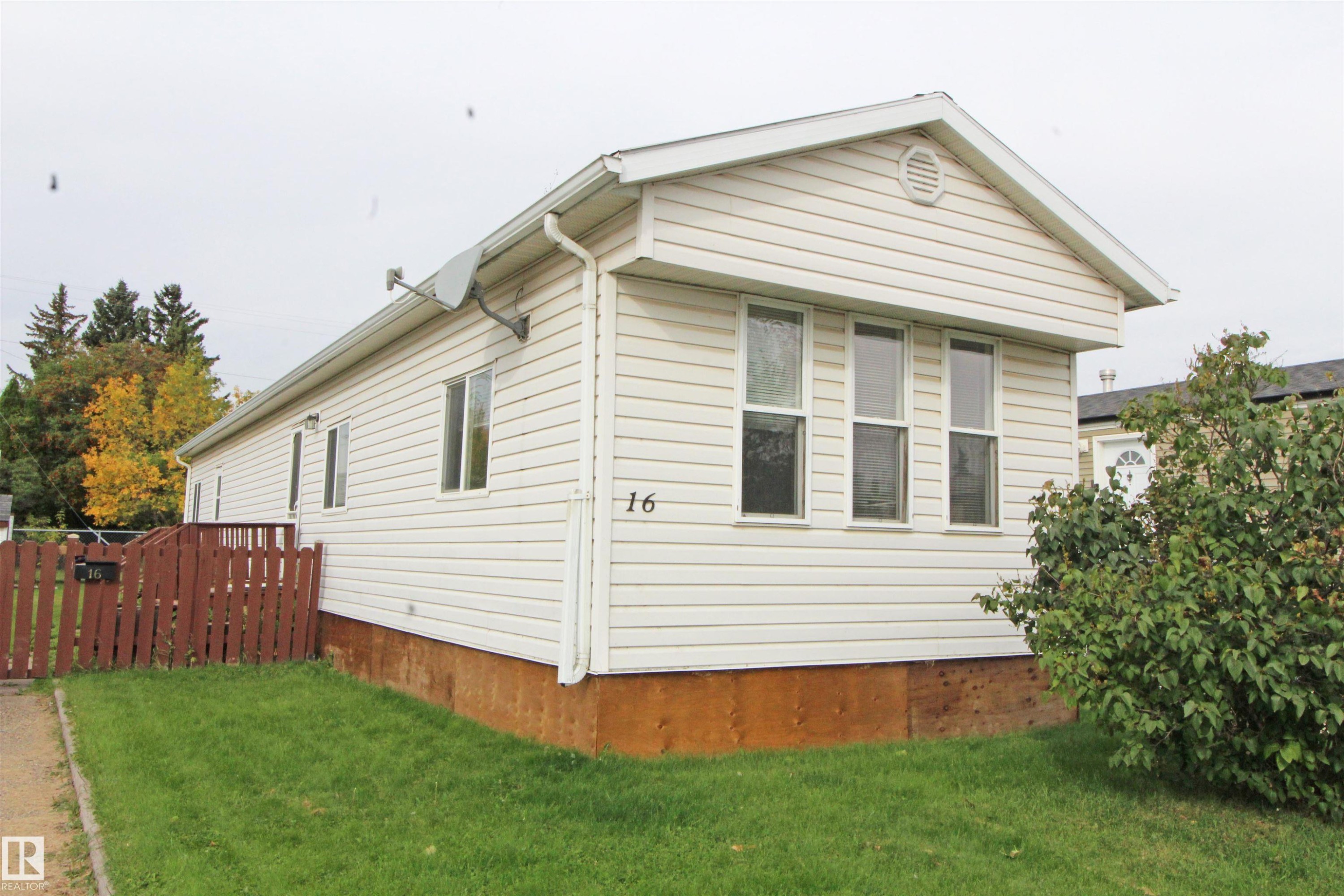 White horizontal siding with a contrasting brown fence and natural green landscaping - #16 4202 45 St, Wetaskiwin, AB
