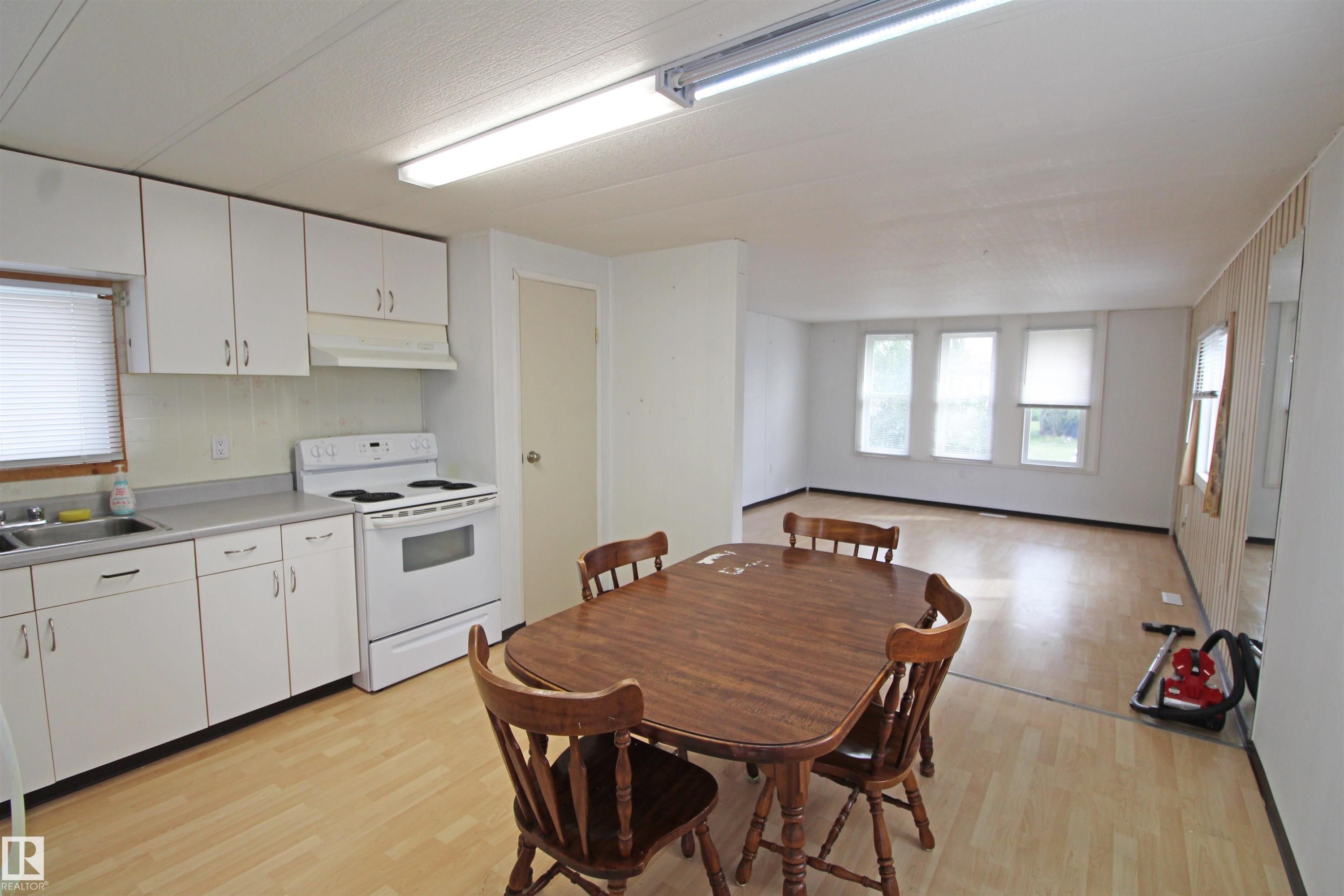 White cabinetry, stainless steel sink, white electric range, wood-finish flooring, multiple windows - #16 4202 45 St, Wetaskiwin, AB