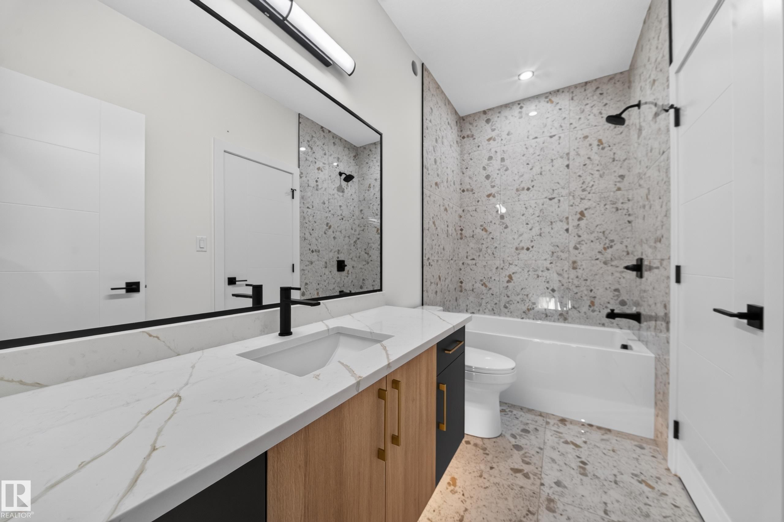 Vanity with quartz countertop and integrated sink, matte black faucet, full-width mirror, tile flooring, and a tiled shower with a bathtub - 13024 186 Avene Nw, Edmonton, AB