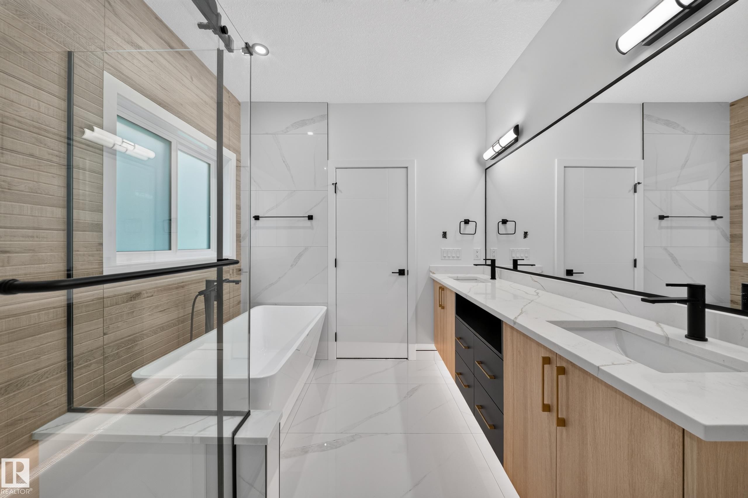 Freestanding soaking tub with a glass shower enclosure, dual vanity with undermount sinks, and wall-mounted lighting fixtures - 13024 186 Avene Nw, Edmonton, AB