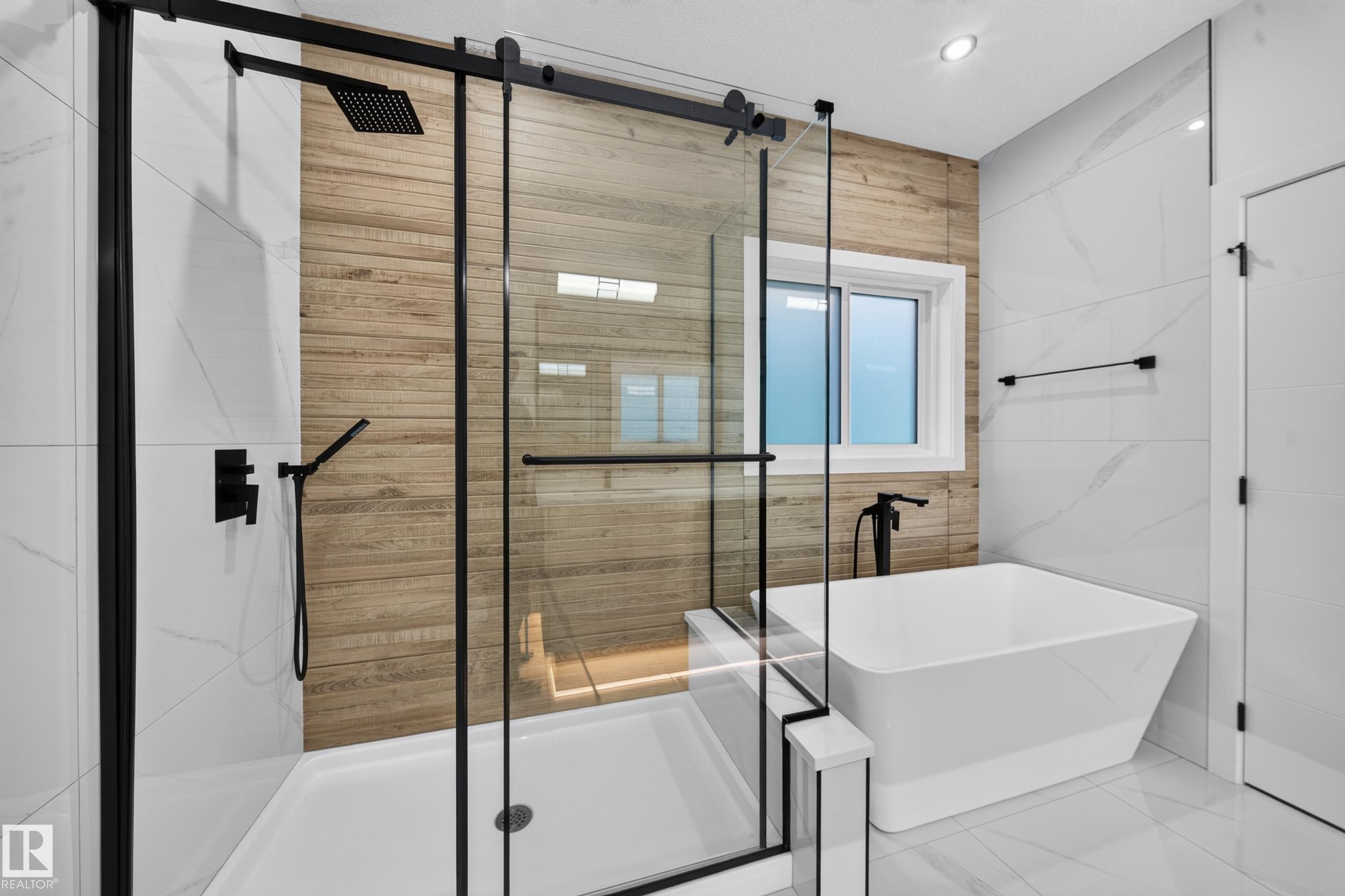 Spacious bathroom featuring a freestanding tub, glass-enclosed shower with black fixtures, and wood-finish accent wall - 13024 186 Avene Nw, Edmonton, AB
