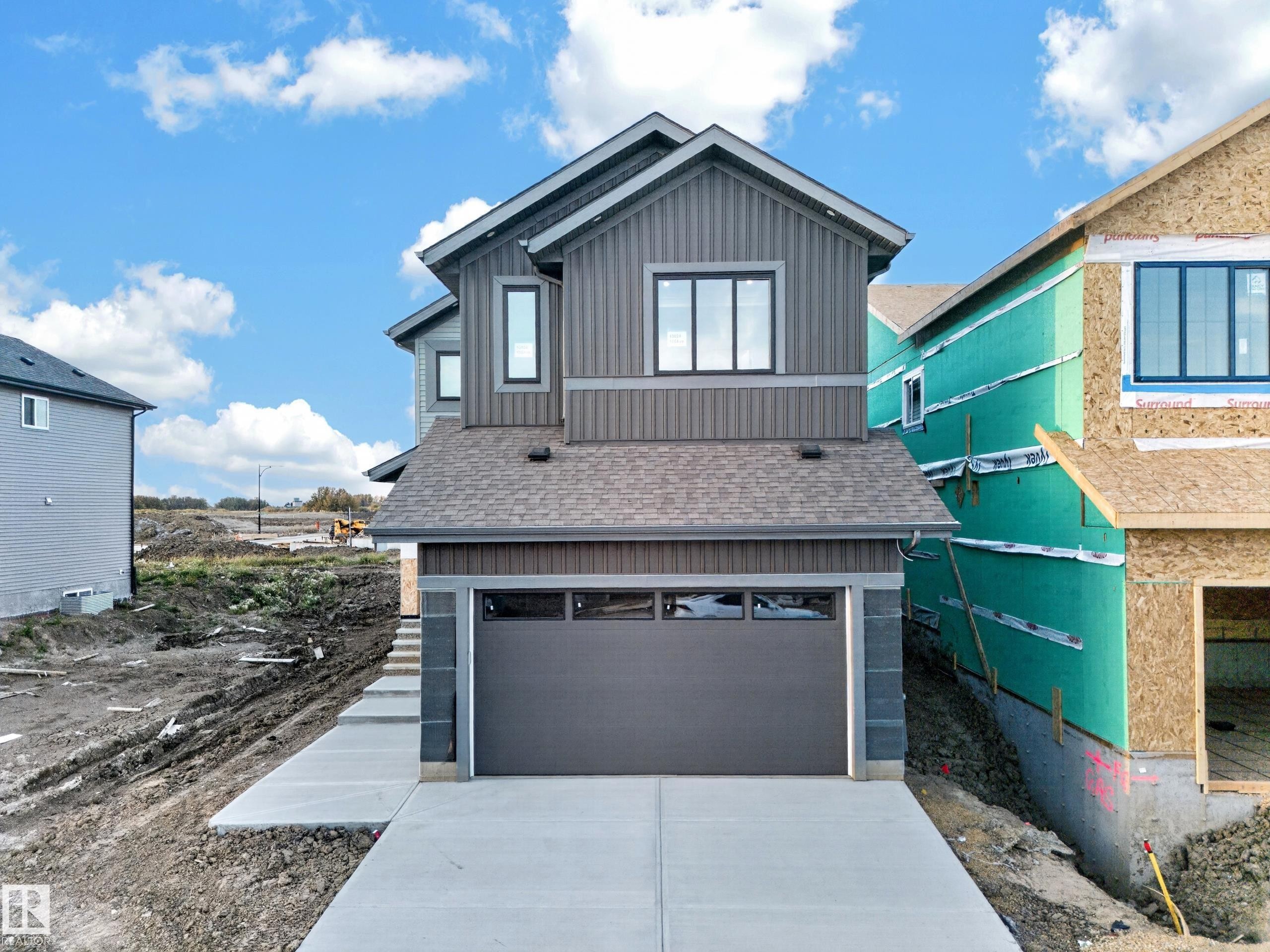 Modern exterior with vertical siding, attached garage, and concrete driveway - 13024 186 Avene Nw, Edmonton, AB