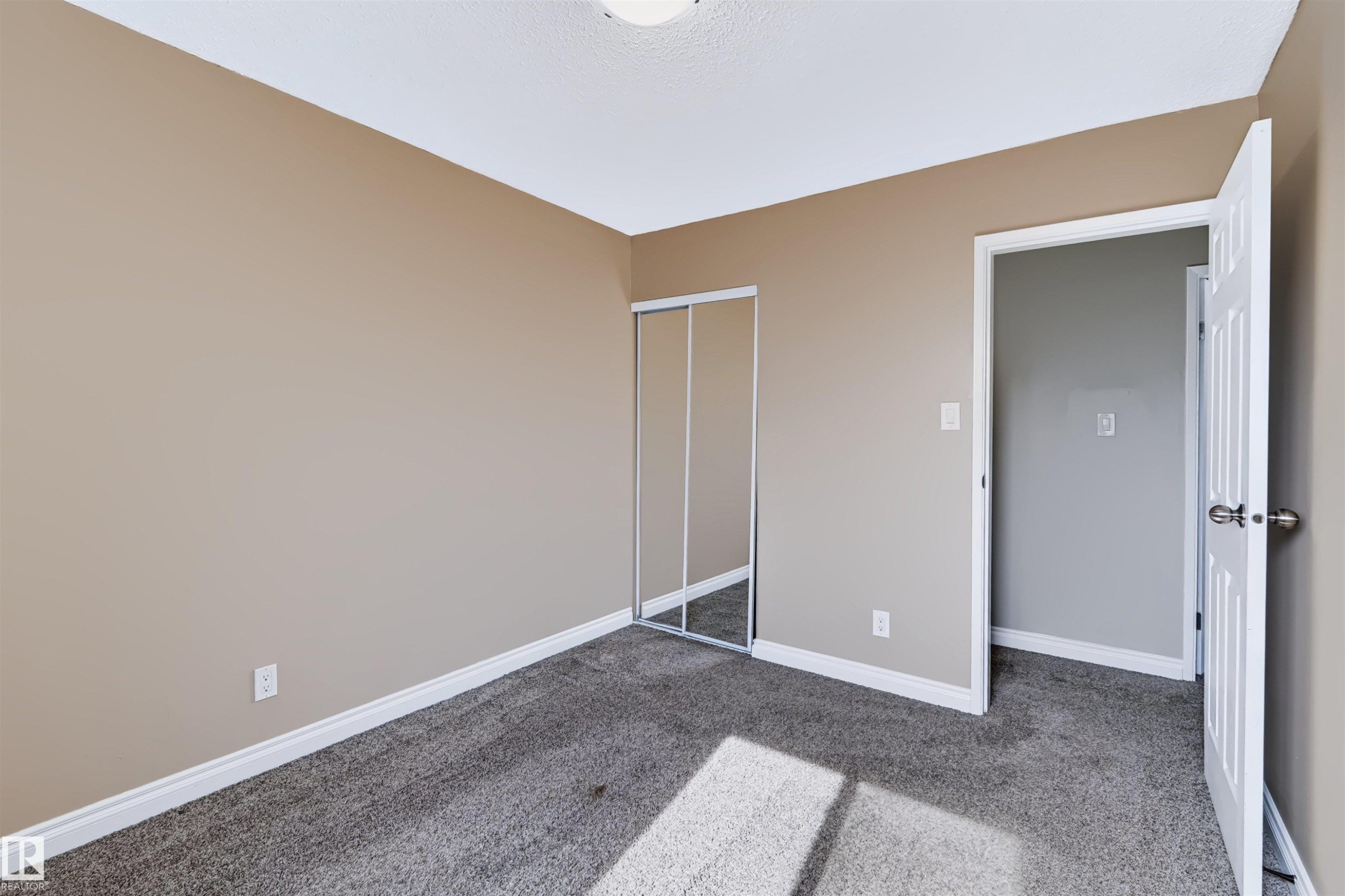 Wall-to-wall carpeting, neutral wall color, white ceiling, white trim, and a white interior door - 155 Primrose Gardens Gardens Nw, Edmonton, AB