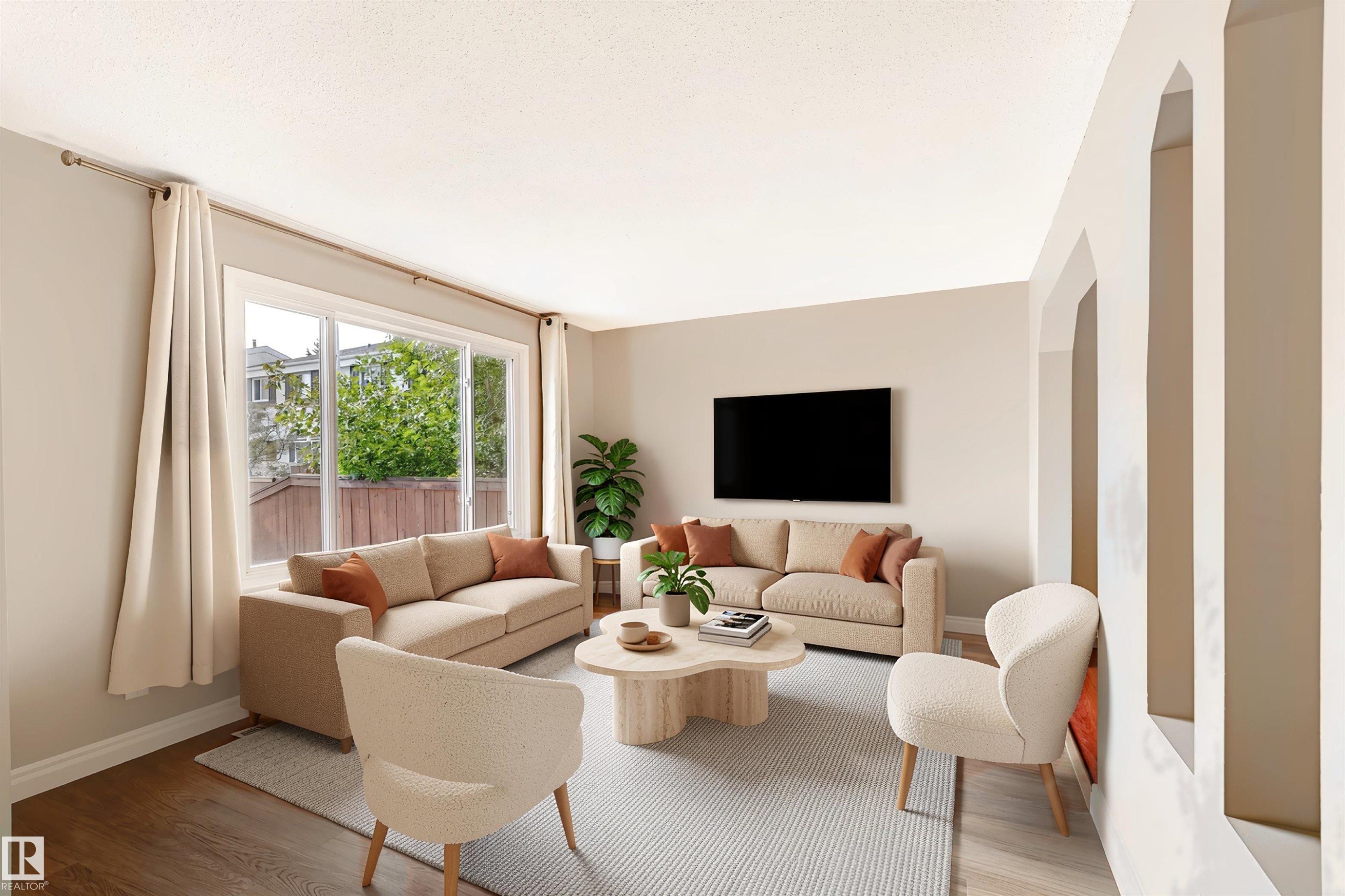 Spacious living area featuring a large window, wood-finish flooring, and arched wall openings - 155 Primrose Gardens Gardens Nw, Edmonton, AB