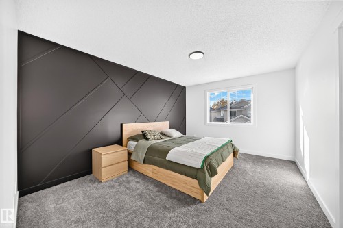 Accent wall featuring geometric paneling, light-colored carpeting, white trim throughout, and a window with a white frame - #27 287 Macewan Rd Sw, Edmonton, AB 