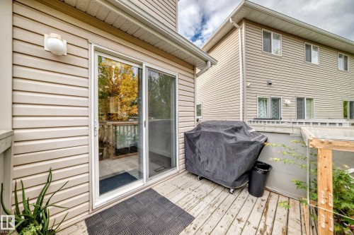 Outdoor deck with wood-finish flooring, sliding glass door, and exterior wall lighting - #27 287 Macewan Rd Sw, Edmonton, AB 