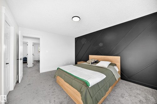 Textured accent wall, neutral carpeting, recessed lighting, white trim, and a door with black hardware - #27 287 Macewan Rd Sw, Edmonton, AB 
