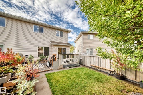 Two-story exterior with light-colored siding, a grass lawn, and a multi-level wood deck - #27 287 Macewan Rd Sw, Edmonton, AB 