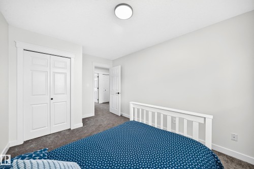 White paneled bi-fold closet doors, neutral wall color, recessed lighting, and dark carpet flooring - #27 287 Macewan Rd Sw, Edmonton, AB 