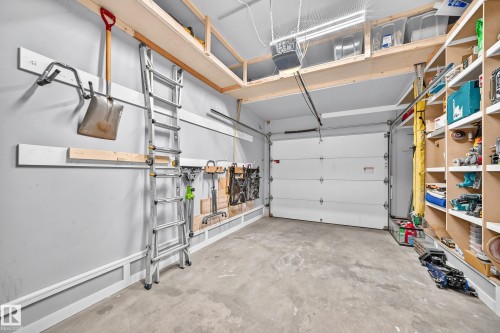 Attached garage featuring a concrete floor, built-in shelving, overhead storage, and wall-mounted organization - #27 287 Macewan Rd Sw, Edmonton, AB 