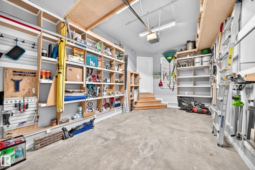 Spacious garage featuring extensive built-in shelving, overhead storage, slatwall organization, and a concrete floor - #27 287 Macewan Rd Sw, Edmonton, AB 