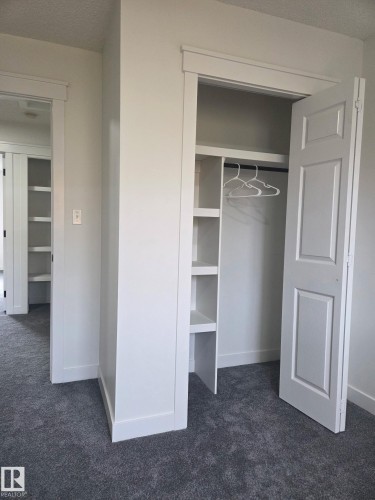 Built-in closet shelving, hanging rod, classic paneled door, and plush gray carpeting - #27 287 Macewan Rd Sw, Edmonton, AB 