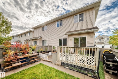 Rear exterior featuring a grass lawn, privacy fencing, wood deck, and sliding glass door access - #27 287 Macewan Rd Sw, Edmonton, AB 