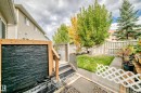 Backyard featuring a slate-tiled water feature, wood-framed deck, fenced perimeter, and a manicured lawn - #27 287 Macewan Rd Sw, Edmonton, AB 