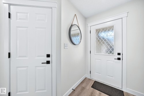 Front entry with wood-finish flooring and a white paneled door featuring decorative glass - #27 287 Macewan Rd Sw, Edmonton, AB 