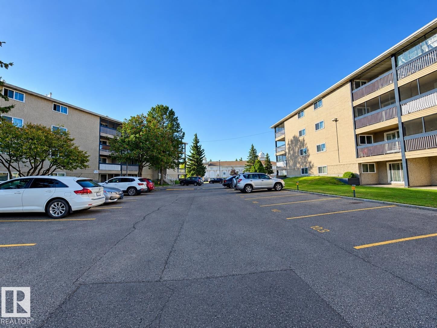 Multi-story building featuring private balconies, surface parking, and landscaped grounds - #108 2624 Mill Woods Rd E Nw, Edmonton, AB
