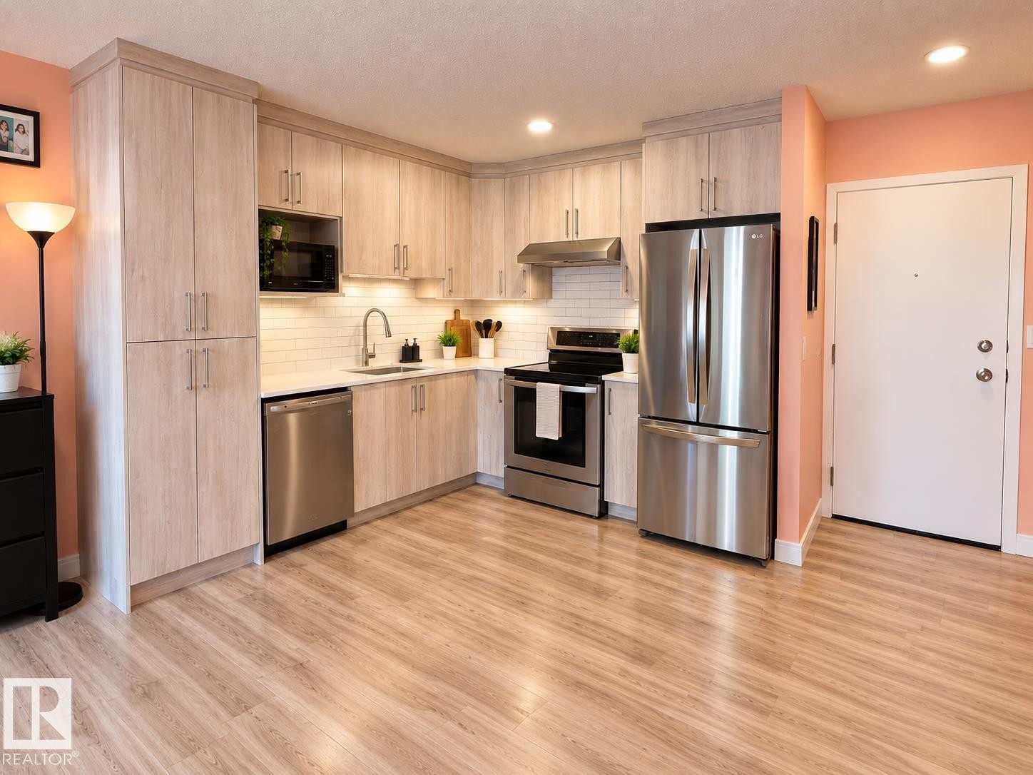 Kitchen featuring wood-finish flooring, light wood-tone cabinetry, stainless steel appliances, a white subway tile backsplash, and recessed lighting - #108 2624 Mill Woods Rd E Nw, Edmonton, AB