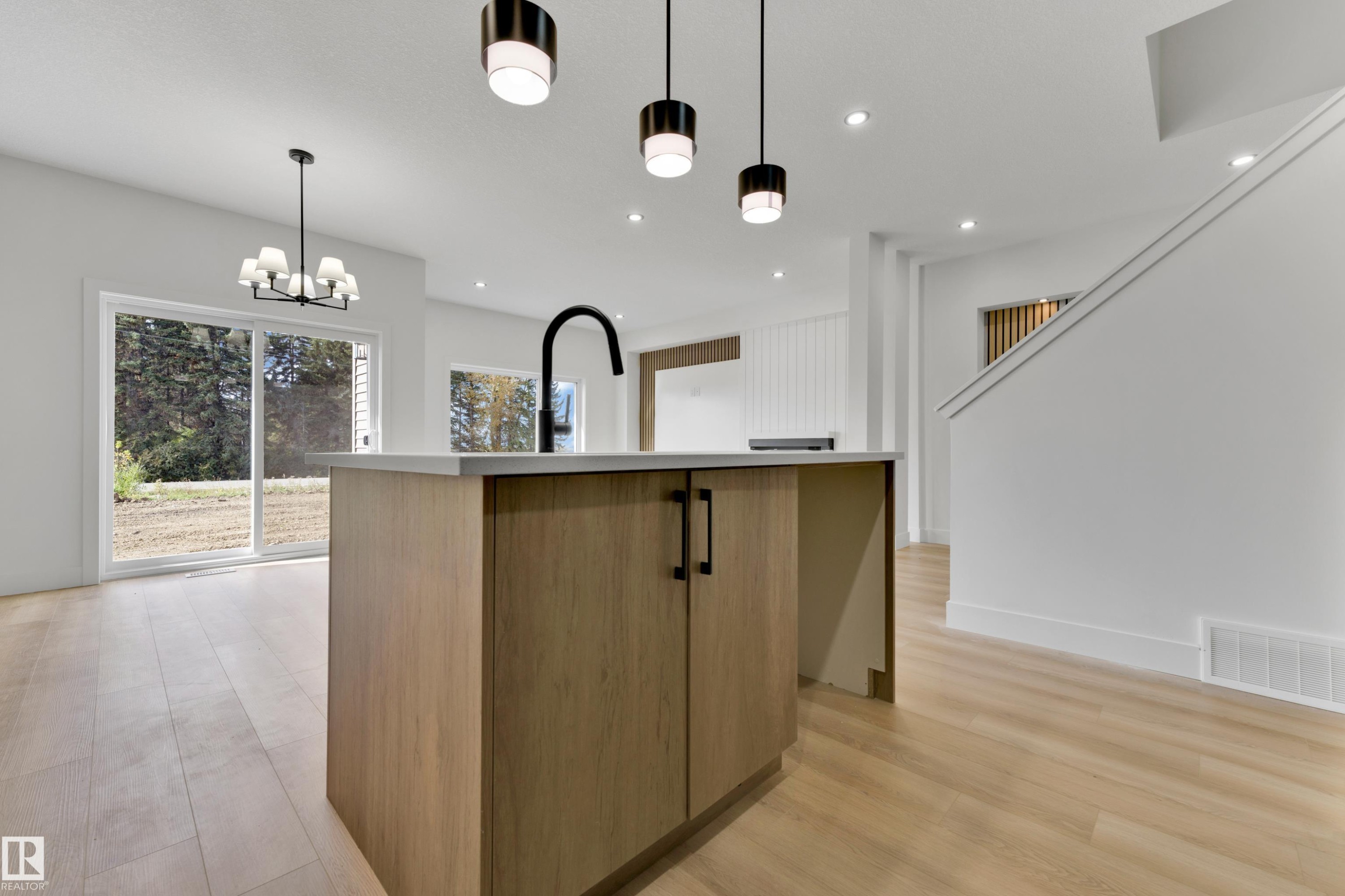 Kitchen island with wood-finish cabinetry, light-toned countertop, and matte black gooseneck faucet - 261 Linden Loop, Leduc, AB