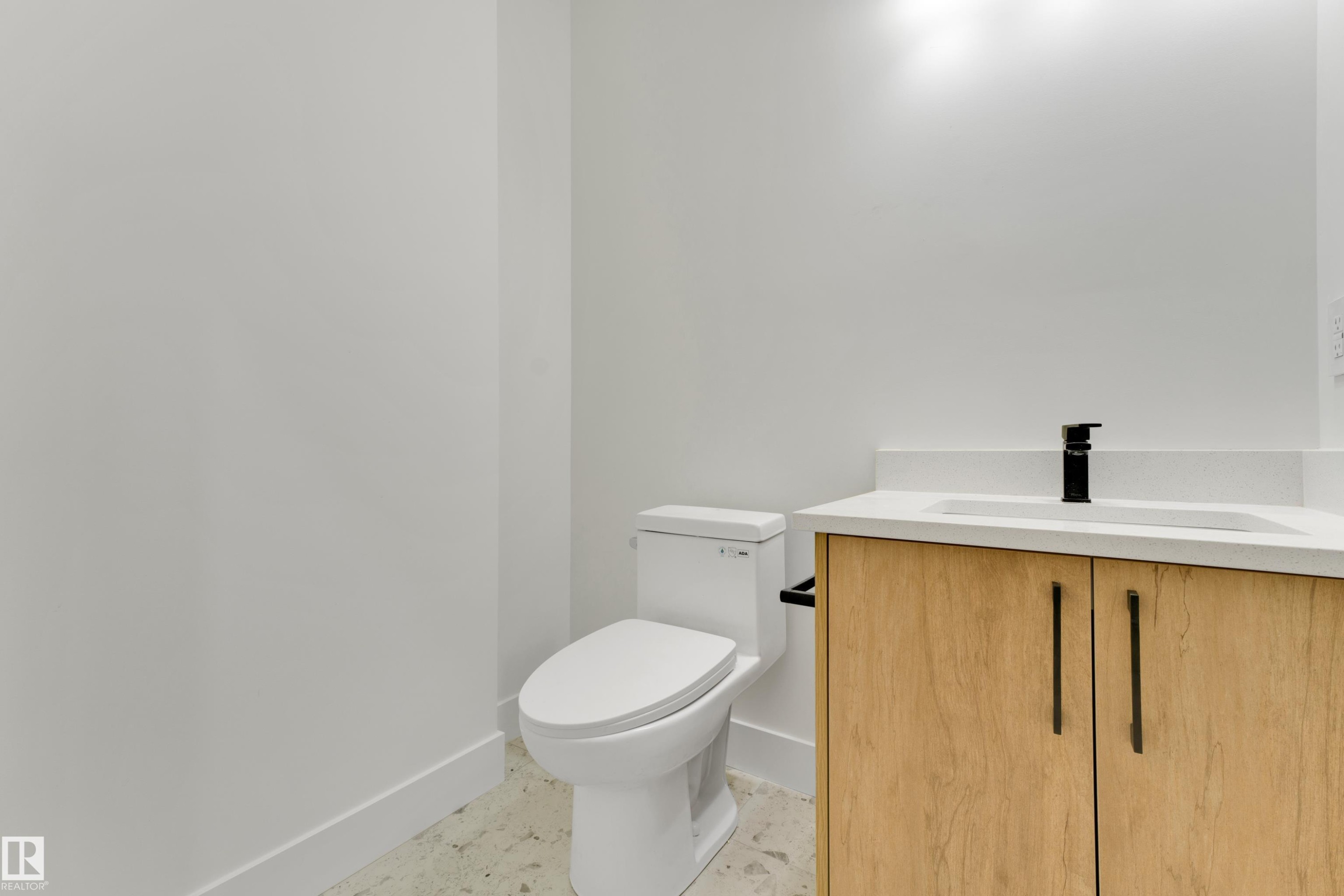 Modern vanity with wood-finish cabinetry, integrated sink, and matte black faucet - 261 Linden Loop, Leduc, AB