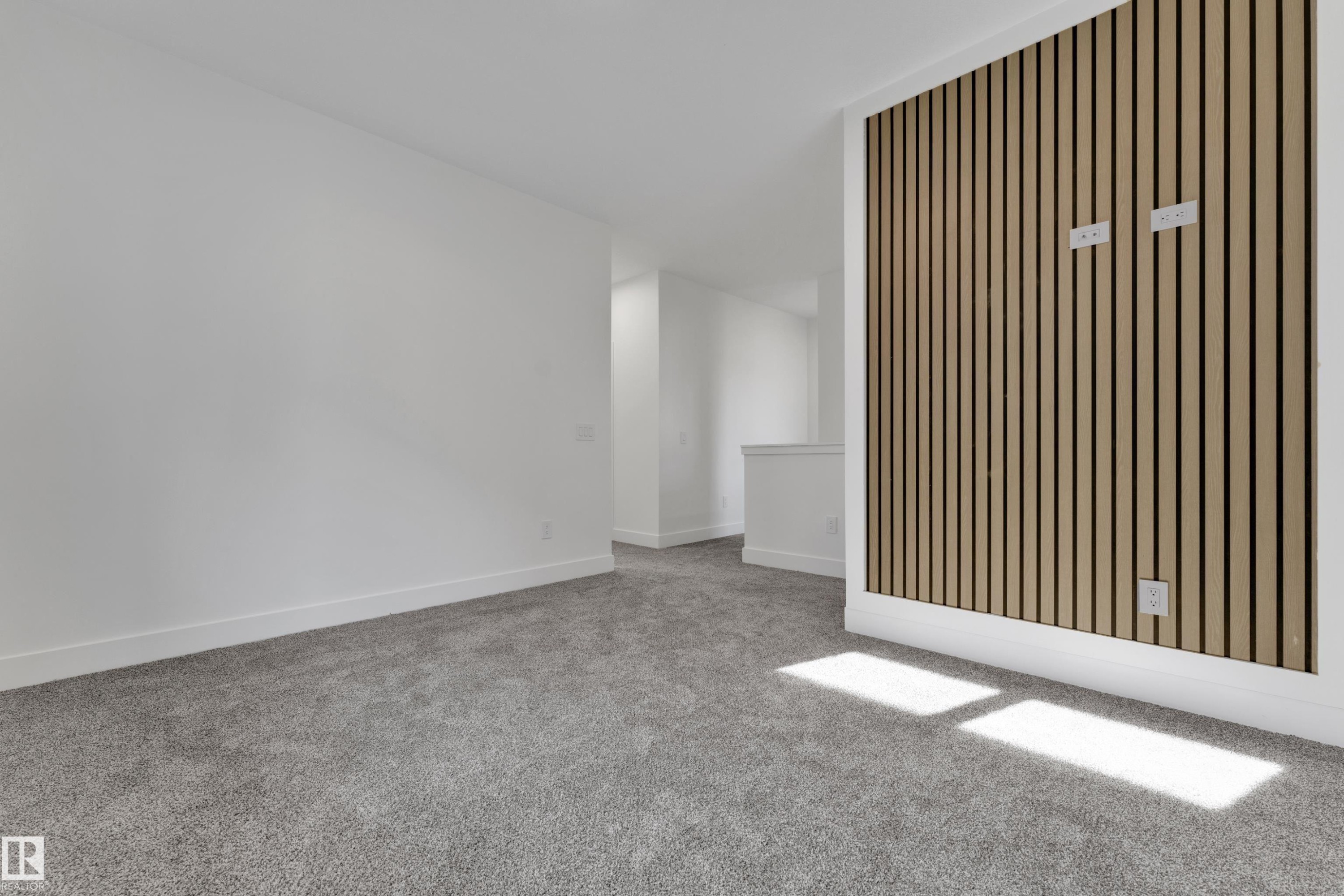 Accent wall featuring vertical wood slat detailing, plush grey carpeting, and white baseboards - 261 Linden Loop, Leduc, AB