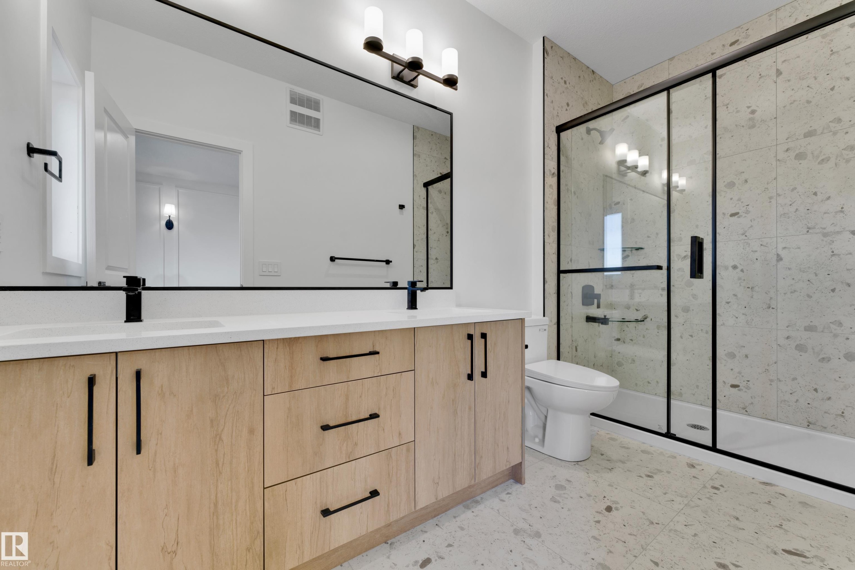 Dual vanity with light wood-finish cabinetry, white countertop, and matte black fixtures - 261 Linden Loop, Leduc, AB