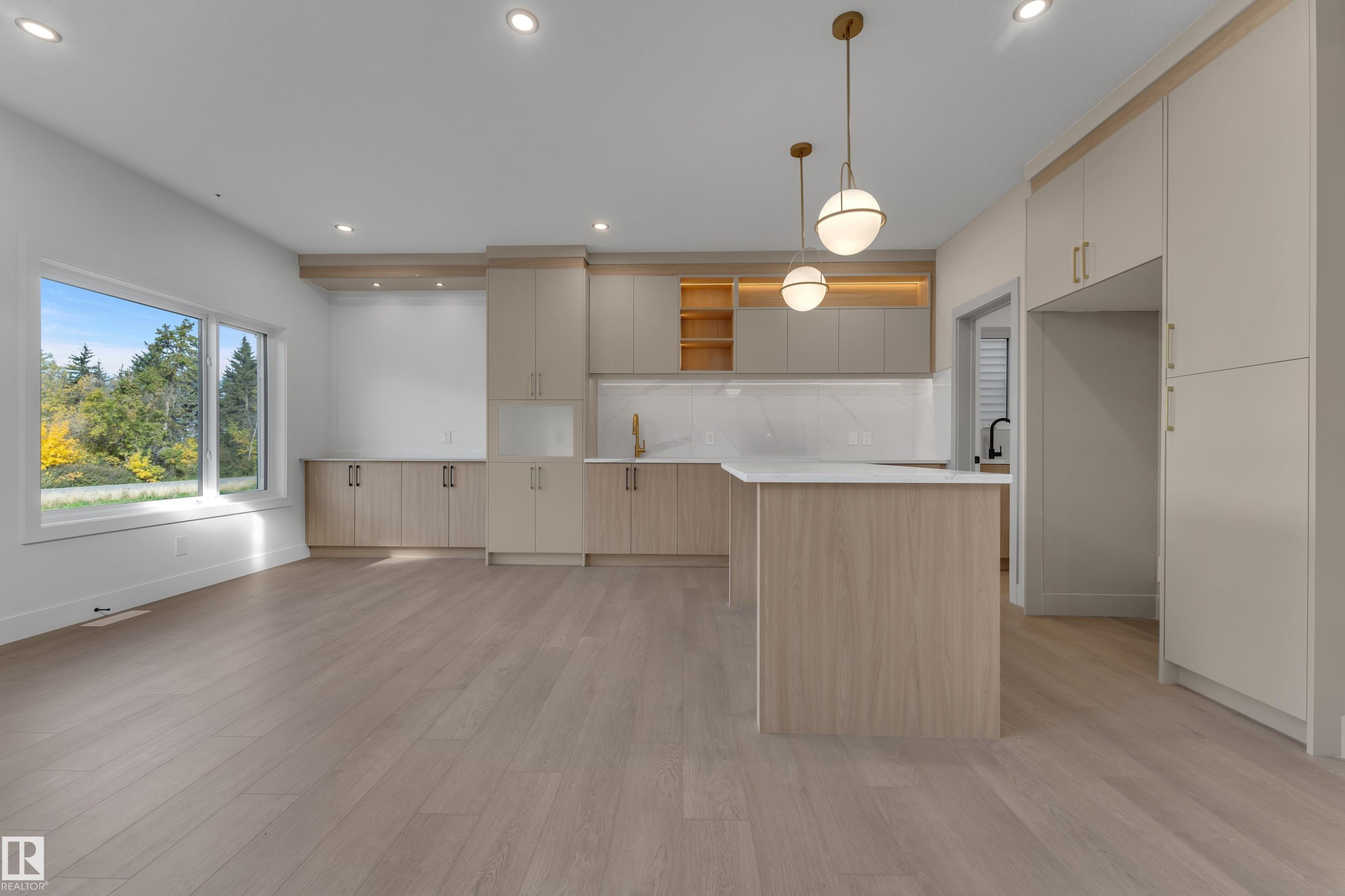 Open-concept living area featuring light wood-finish flooring, a kitchen island with a white countertop, and recessed lighting - 247 Linden Loop, Leduc, AB
