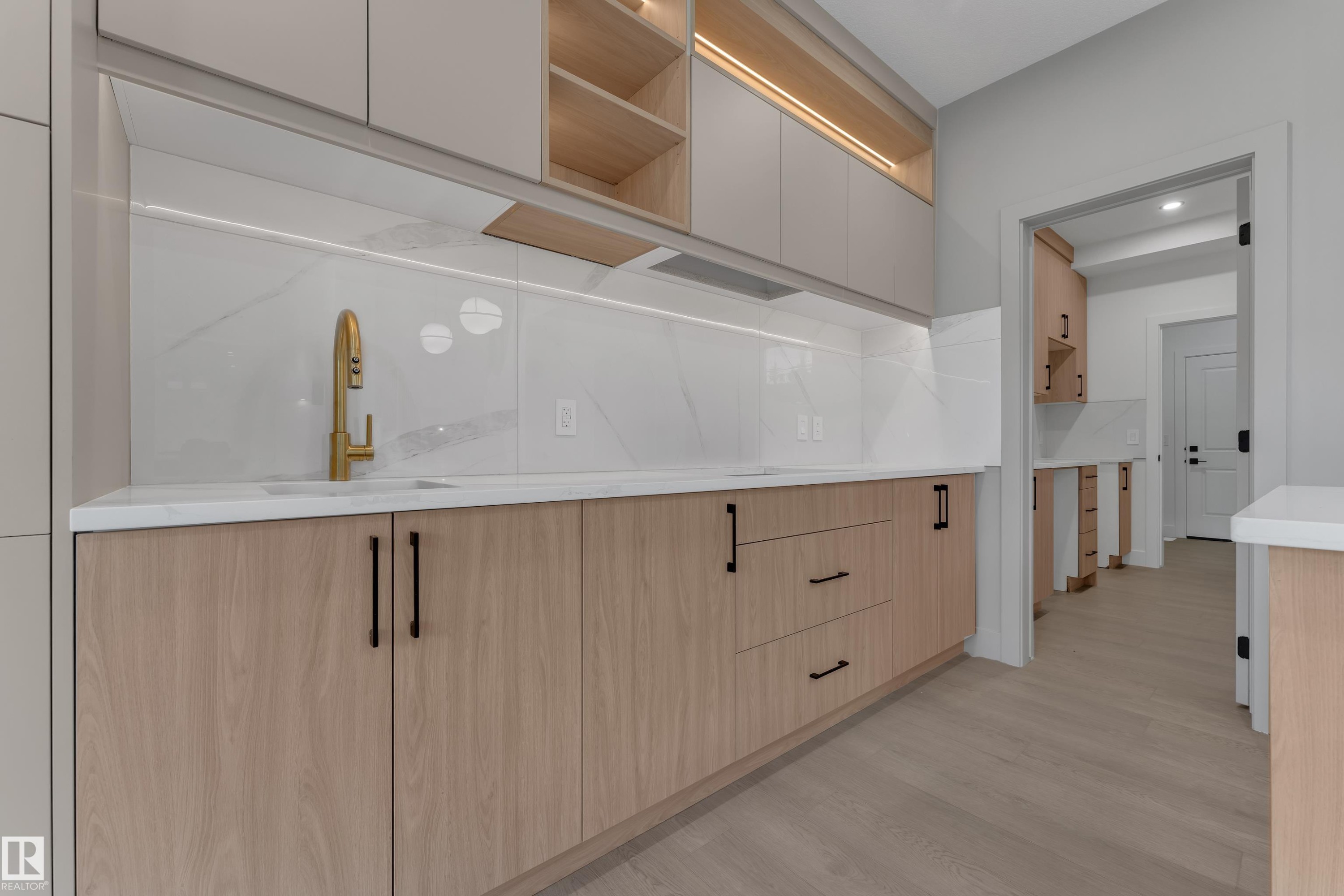 Modern kitchen featuring light wood-finish cabinetry, white stone countertops, and a white tile backsplash - 247 Linden Loop, Leduc, AB