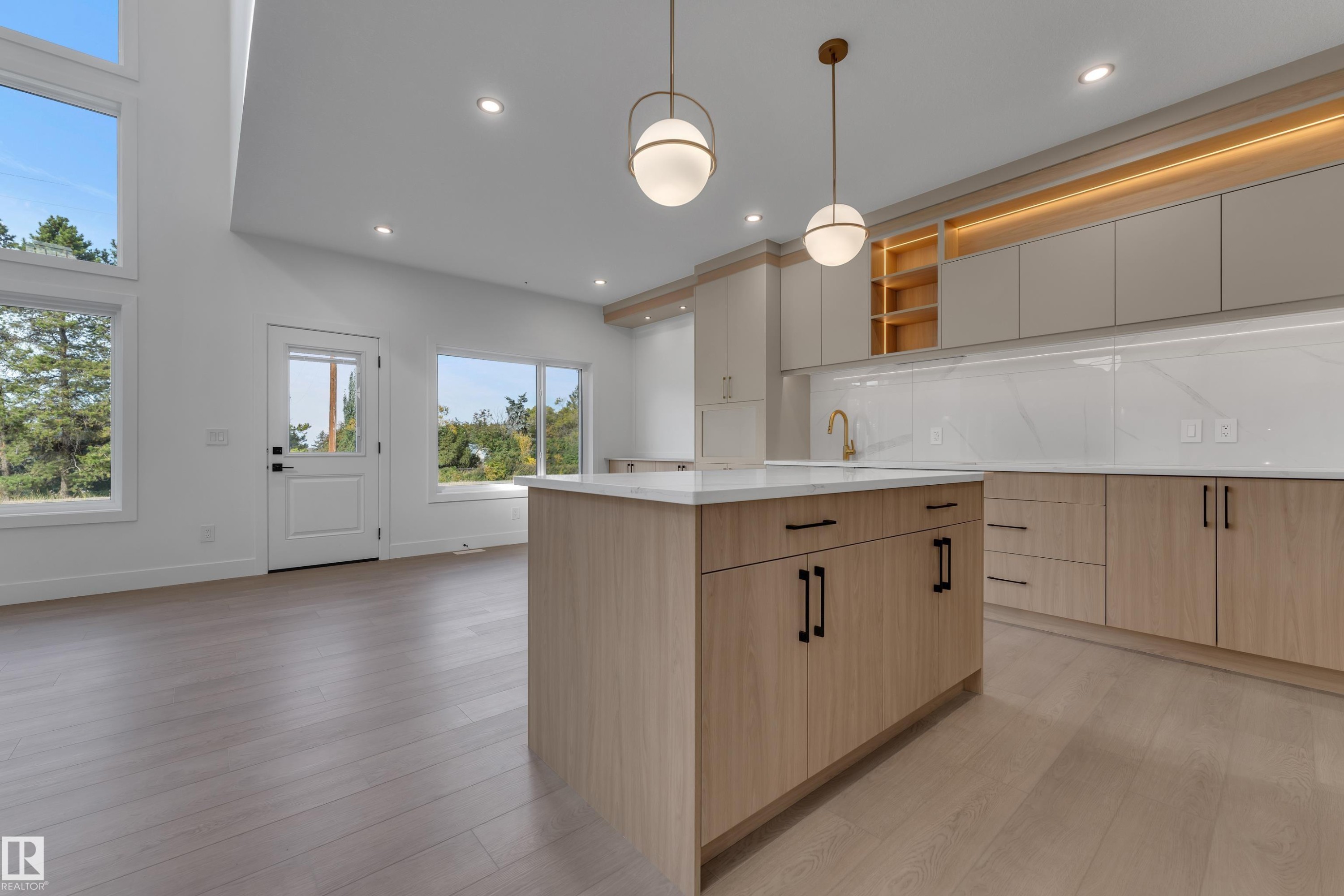 Kitchen featuring wood-finish flooring, a central island with countertop, flat-panel cabinetry, and wall-mounted lighting - 247 Linden Loop, Leduc, AB