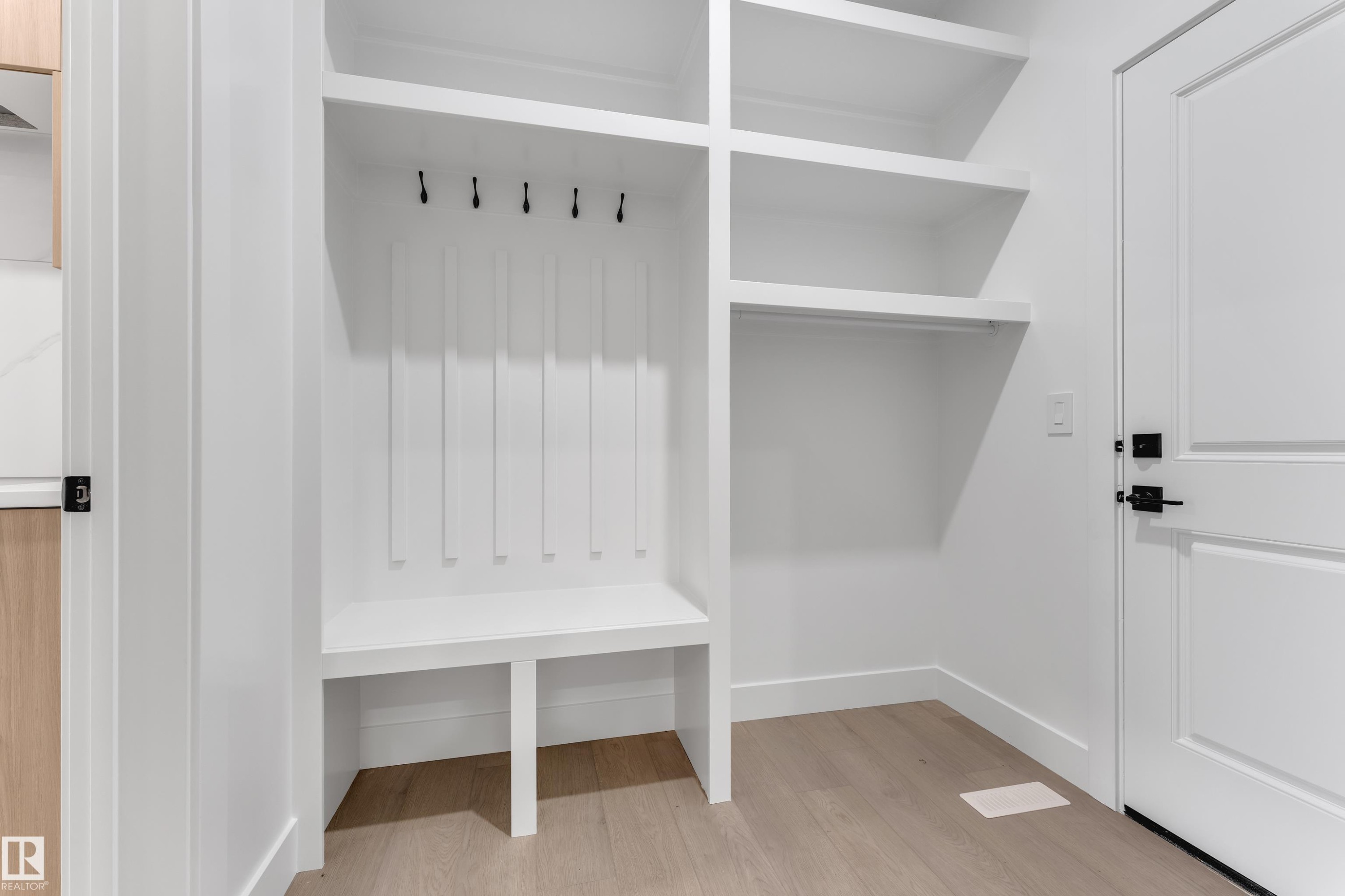 Built-in white storage unit featuring shelving, an integrated bench, and wall-mounted hooks - 247 Linden Loop, Leduc, AB