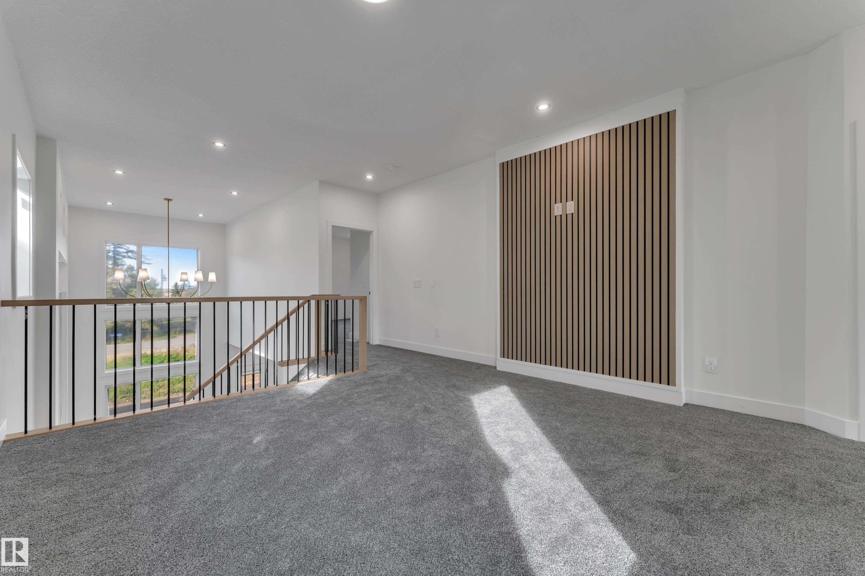 Open-concept upper level with recessed lighting, light-toned wood slat accent wall, and gray carpeting - 247 Linden Loop, Leduc, AB