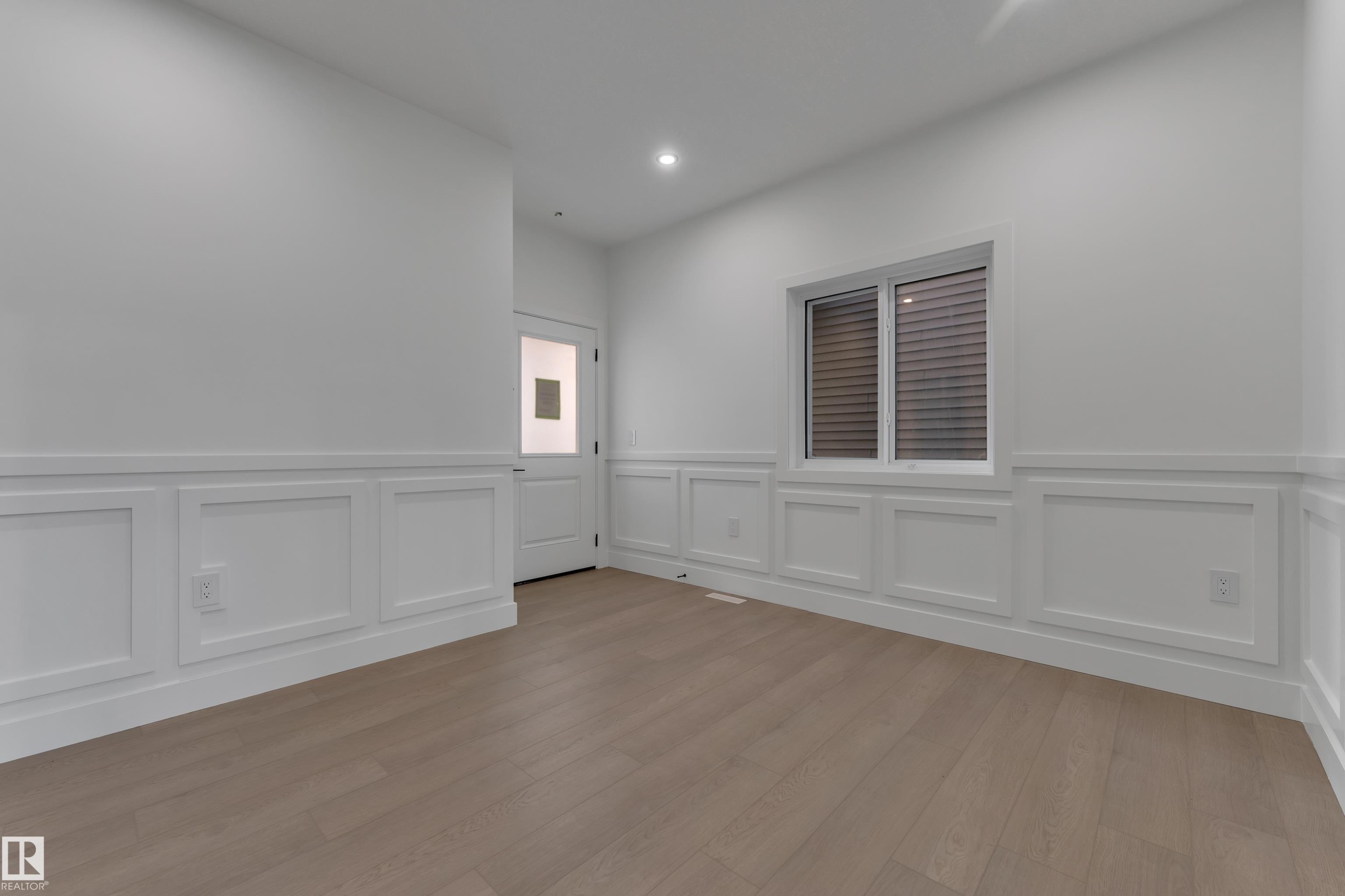Light wood-finish flooring, white walls, wainscoting detail, recessed lighting, and a white interior door with a frosted glass pane - 247 Linden Loop, Leduc, AB