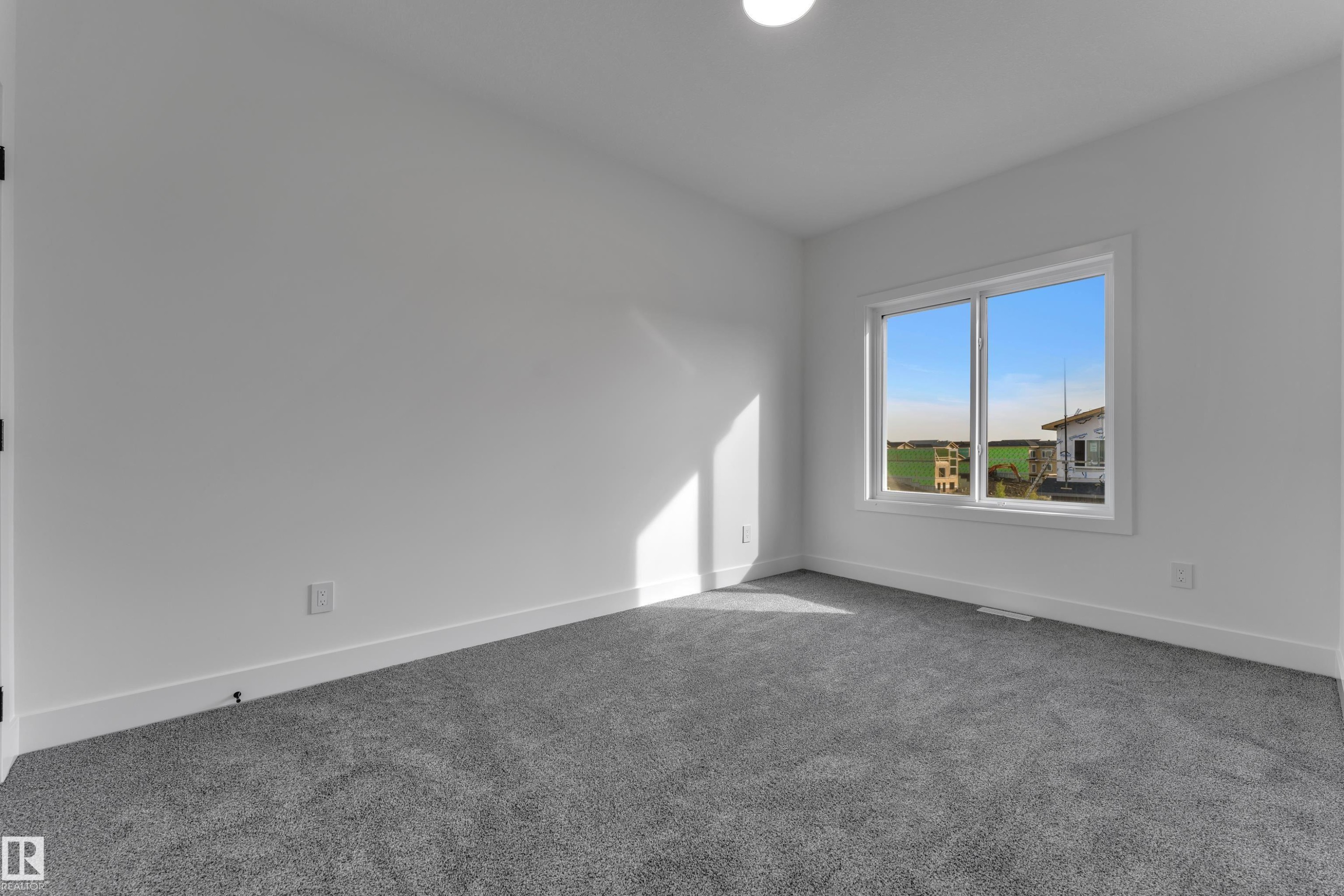Bright interior space with white walls, gray carpeting, a single window, and a flush-mount ceiling light - 247 Linden Loop, Leduc, AB