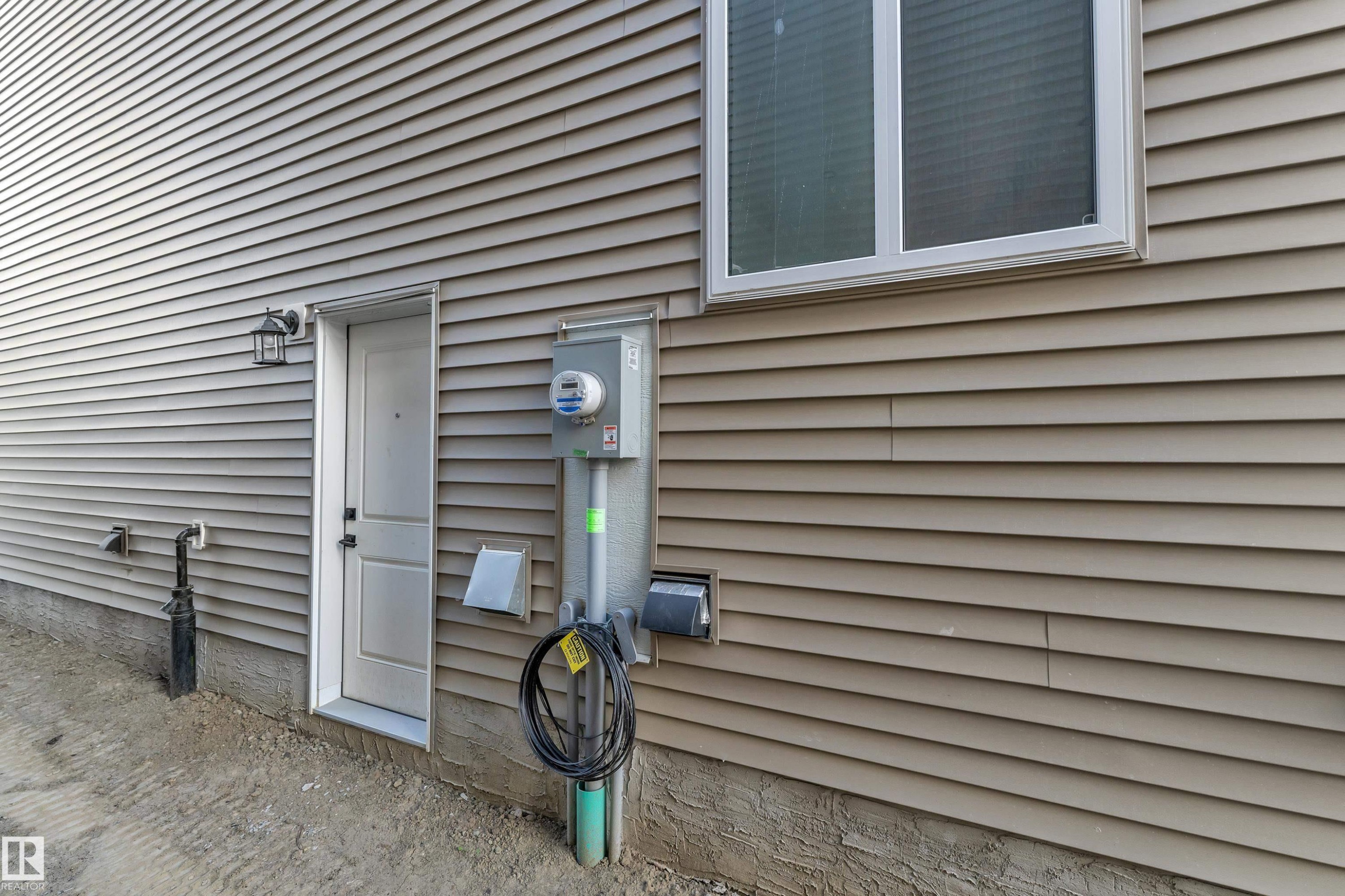 Beige horizontal siding with a white trim window and a white door - 247 Linden Loop, Leduc, AB