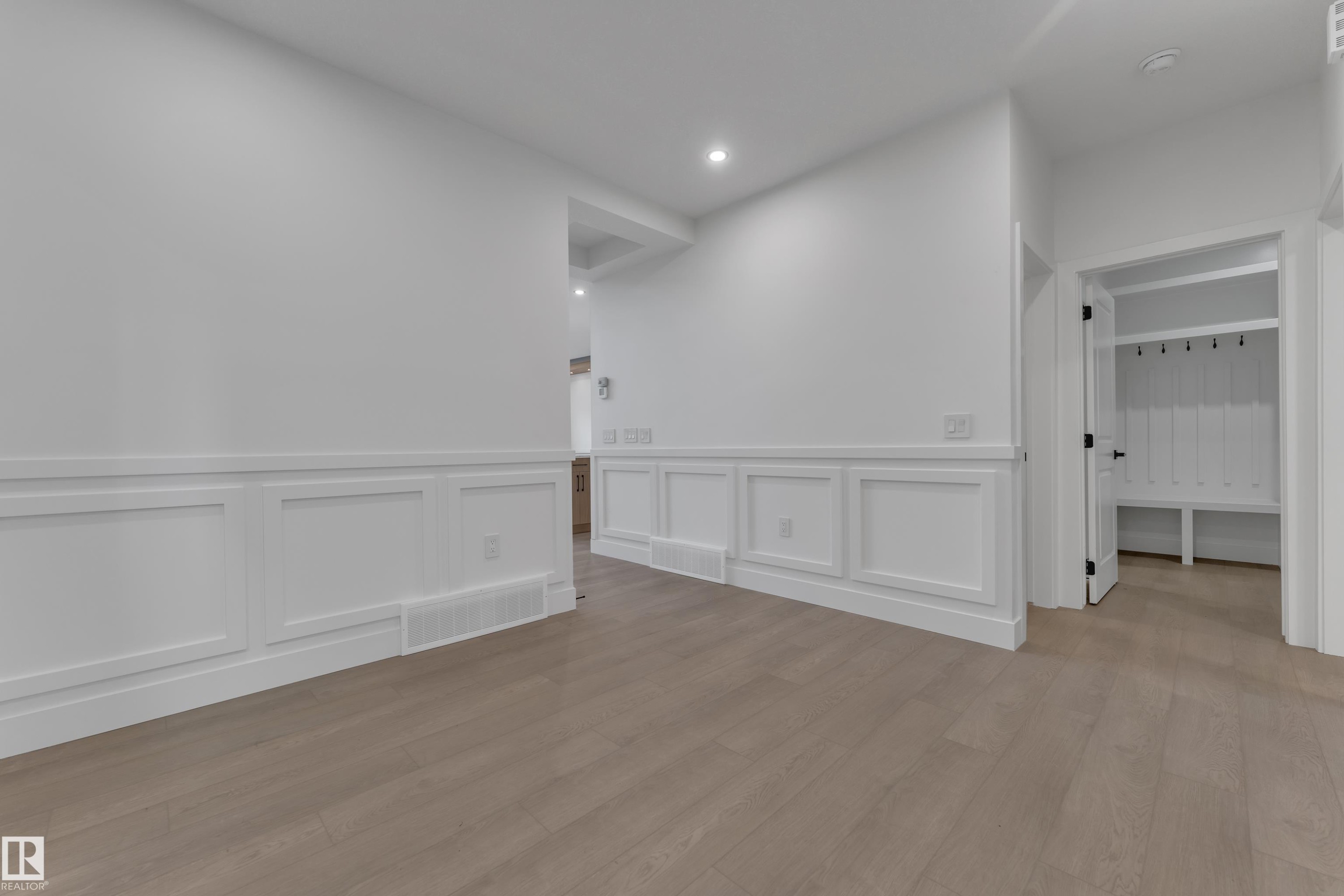 Light wood-finish flooring, wainscoting paneling, recessed lighting, and a built-in hall tree with storage bench and hooks - 247 Linden Loop, Leduc, AB