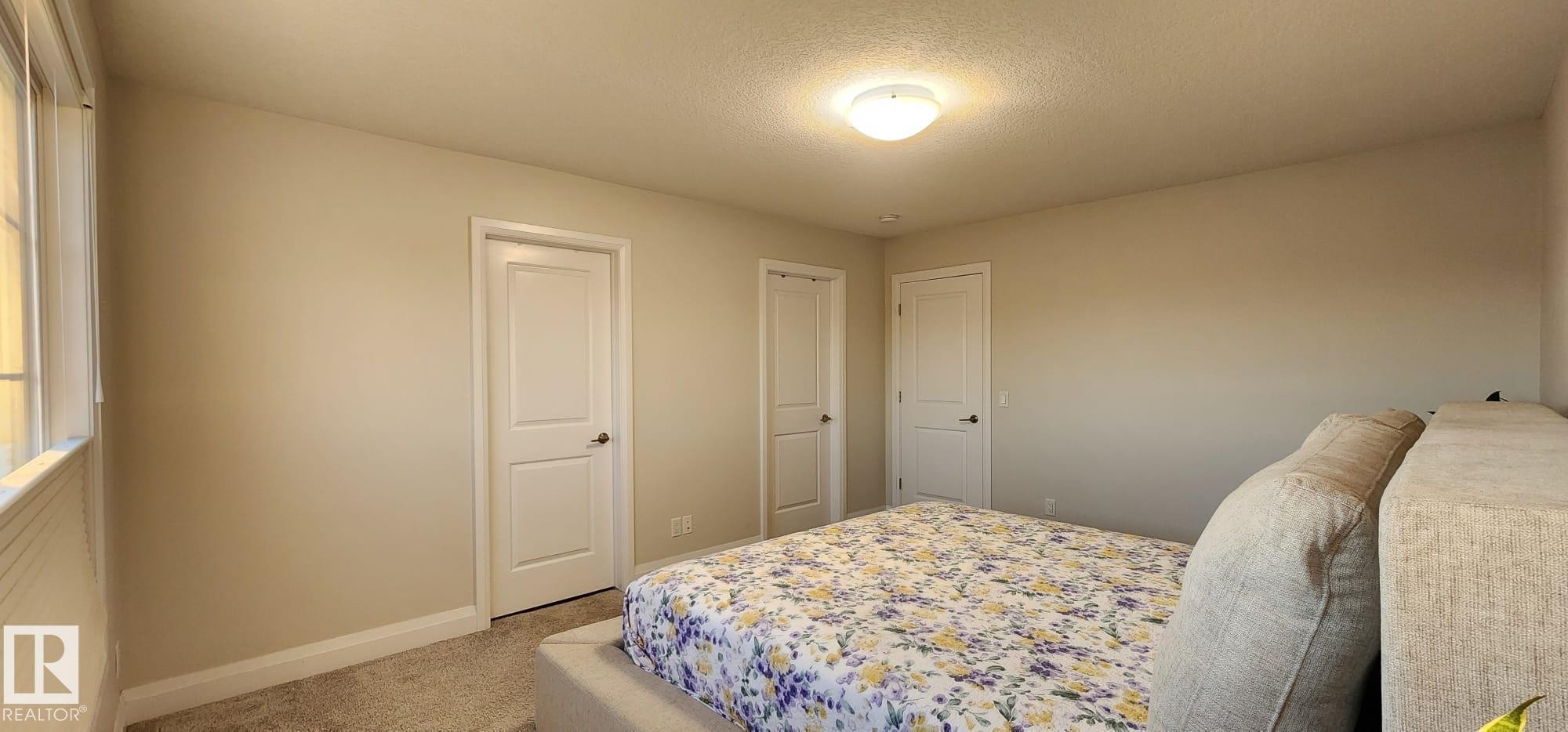 Carpeted flooring, neutral wall tones, multiple panel doors, and a ceiling-mounted light fixture - 3779 Cherry Loop Sw, Edmonton, AB