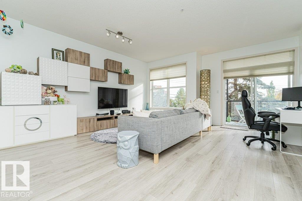 Light wood-finish flooring throughout, track lighting, and a built-in media console with storage - #202 9503 101 Av Nw, Edmonton, AB